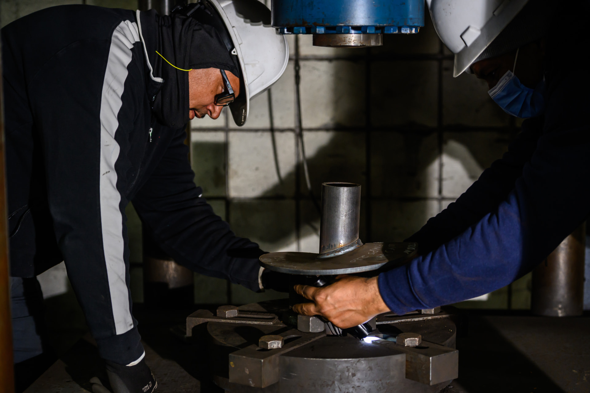 Technicians inspecting a helix-to-shaft weld on a test fixture